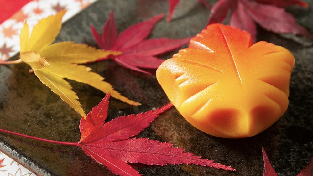 紅葉をモチーフにした和菓子とパルファンサトリ「ワサンボンEX」のボトルが並ぶ写真
