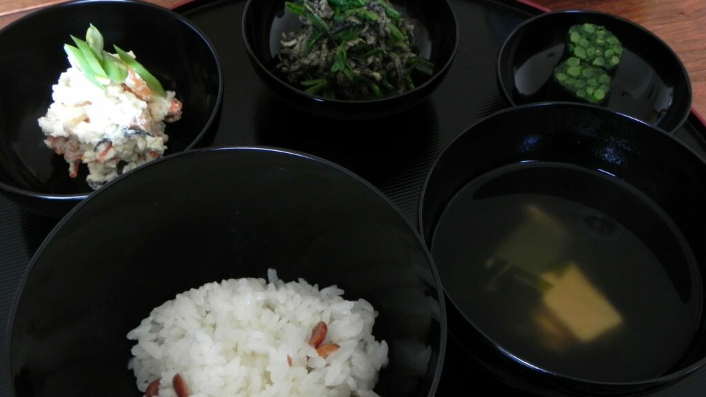 応量器（じはつ）の五つ椀。入れ子になった黒い椀と、ご飯・汁物・副菜が並ぶ