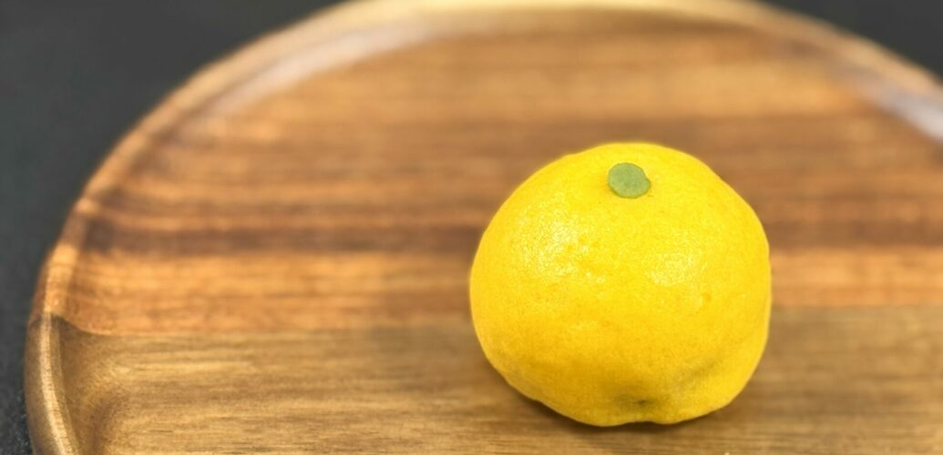 塩野の柚子饅頭（ゆずまんじゅう）。木の丸盆にのせた黄色い饅頭から 柚子の香り