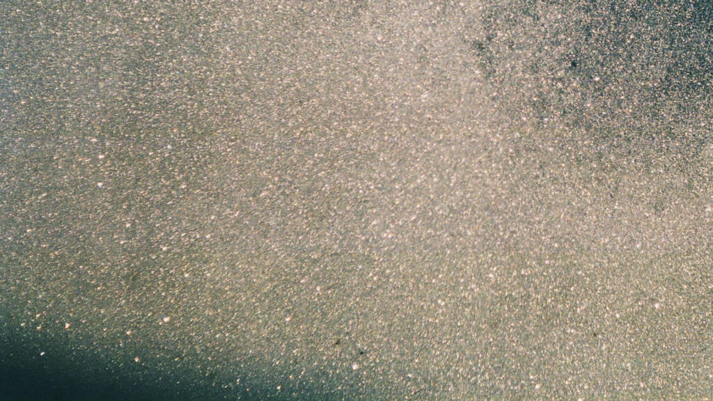 Close-up of fine fragrance crystals scattered like stardust on a dark surface